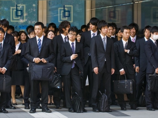 Tokyo, Giappone - 29 ottobre 2009: Impiegati giapponesi in piedi fuori da un edificio per uffici nel distretto finanziario di Tokyo Giappone